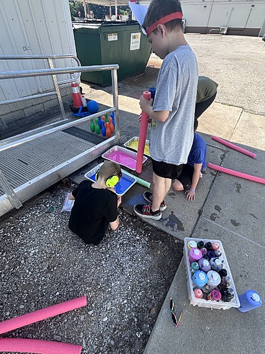 An adult artist creating a bright painting during a community art session.